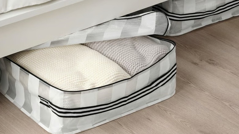 A white and clear underbed storage case with linens inside