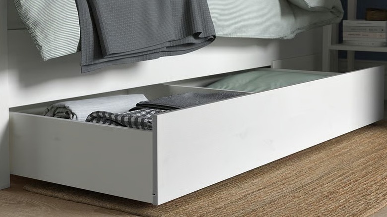 A sectioned white pull out drawer under a bed