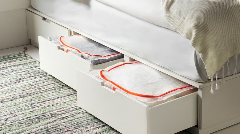 Two white orange storage boxes inside a drawer in a bed