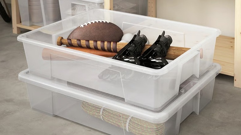 Two clear plastic boxes being used for storing sports equipment