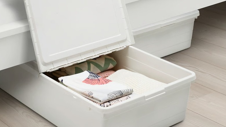 A white underbed storage box with its lid open