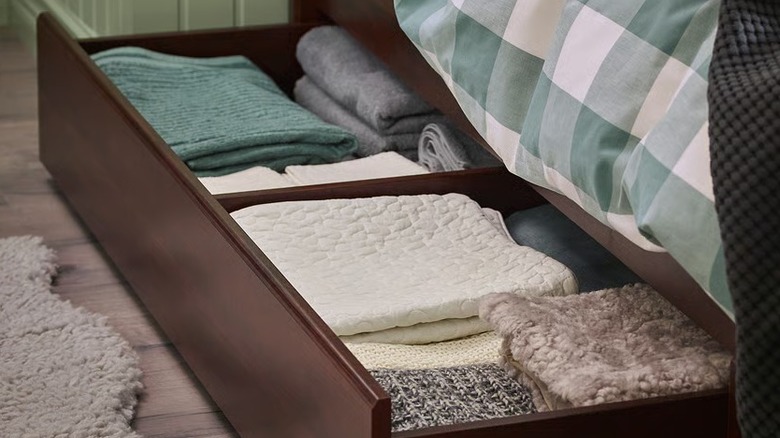 A rich brown underbed storage box filled with towels and linens