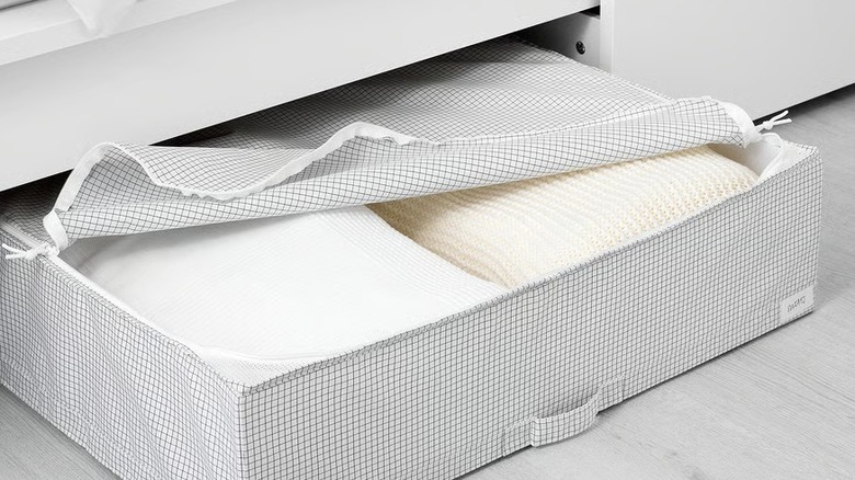 A black and white checkered storage case under a bed