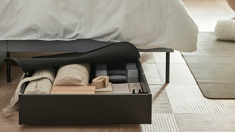 A filled black case with wheels under a bed