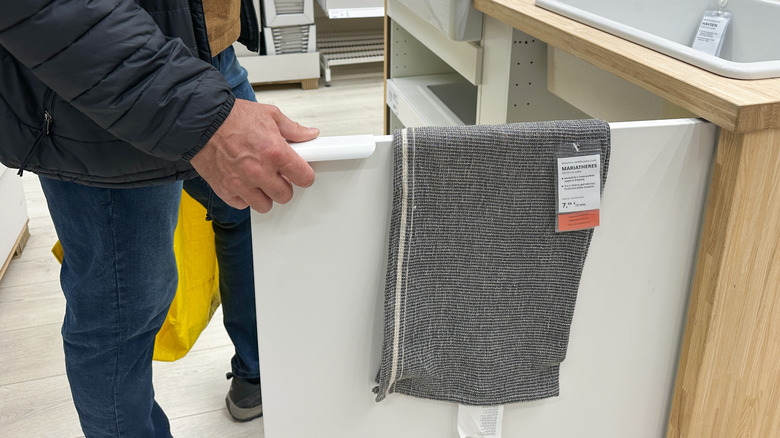 Man opens drawer to inspect gray fabric in Ikea showroom, showcasing modern storage solutions and home decor ideas
