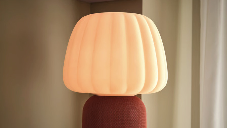 IKEA's KULGLASS Bluetooth speaker lamp in red-brown/pink on a table