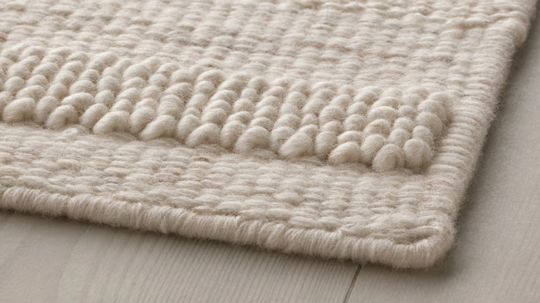 Closeup of BRÖNDEN low pile rug in beige on the floor