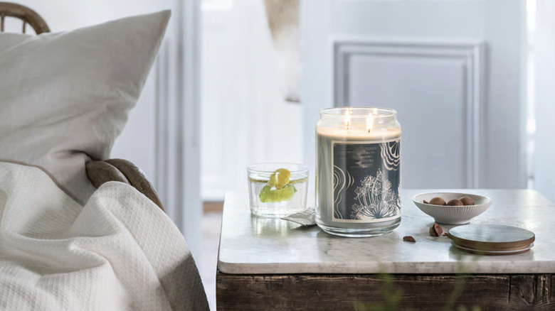 IKEA's BUKETTAPEL scented candle on a nightstand next to a bed