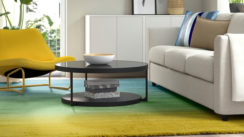 blue, green, and yellow rug beneath a coffee table, yellow chair, and cream sofa