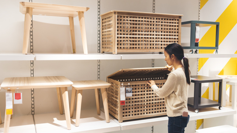 Woman looking at IKEA furniture on shelves in showroom