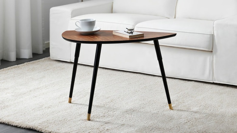 Side table holding a book and a teacup in front of a white sofa