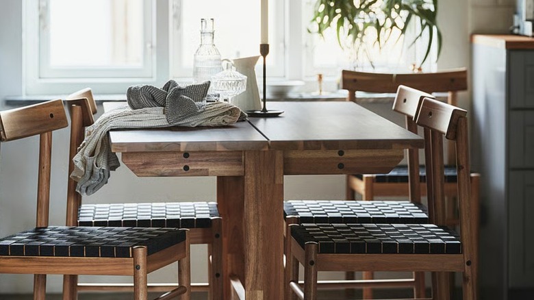 acacia wood table with woven seat chairs in a bright kitchen