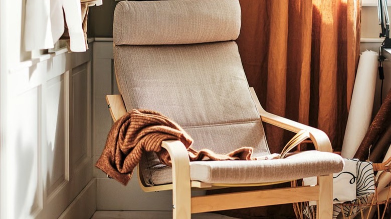 close up of the POÄNG Armchair in the corner of a room next to a curtain