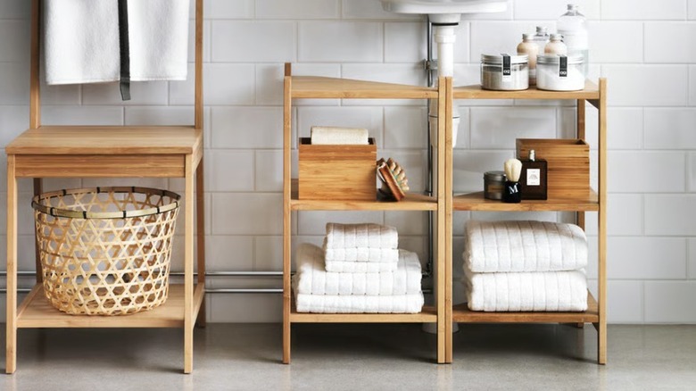 Light wood shelves holding towels and storage, beneath a pedestal sink