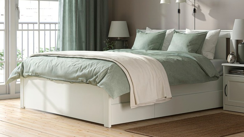 white bed frame with sage green beddings in a bedroom with French doors to patio area