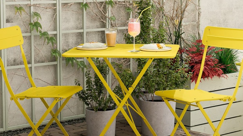 bright yellow patio cafe table and chair set arranged for dining on a patio with trellis and plants