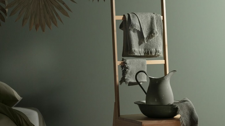 towels displayed on a ladder in front of a bowl and pitcher