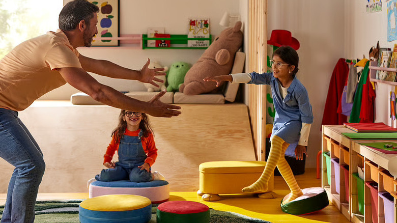 Man and children playing a game while stepping on the GREJSIMOJS floor cushions