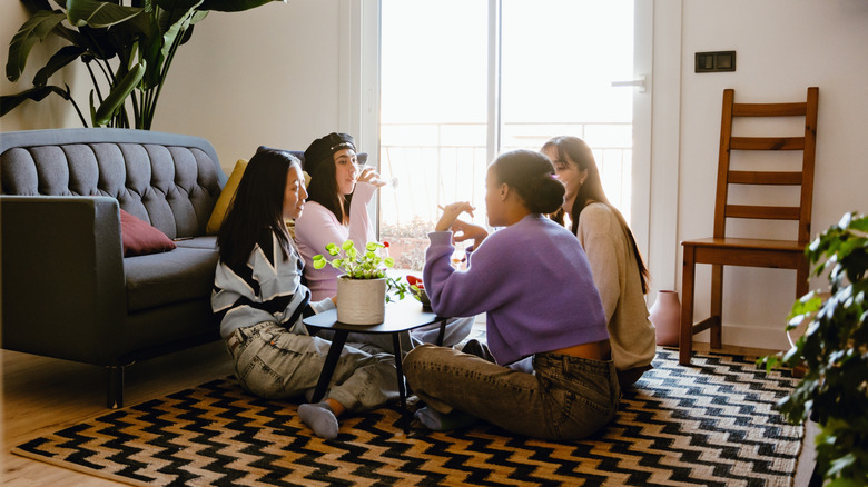 Four women sitting on rug around a coffee table