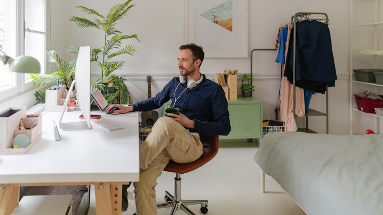 Man working in well-lit, large home office in his bedroom