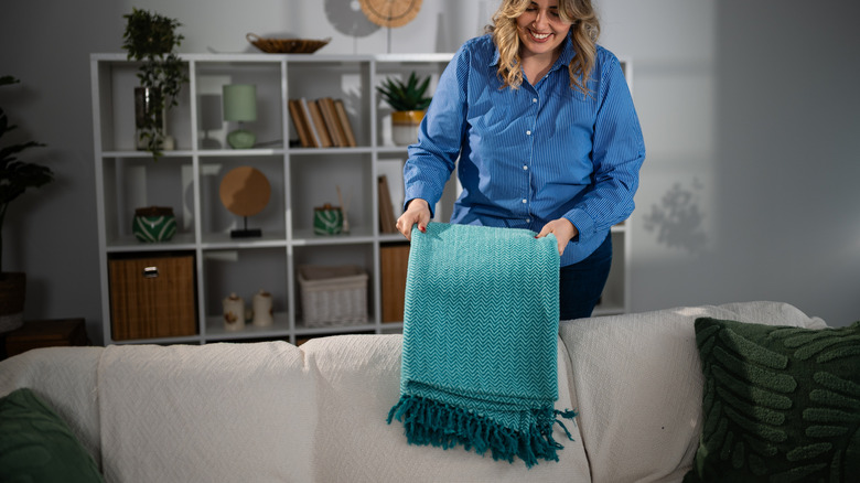 Woman folding blankets on couch