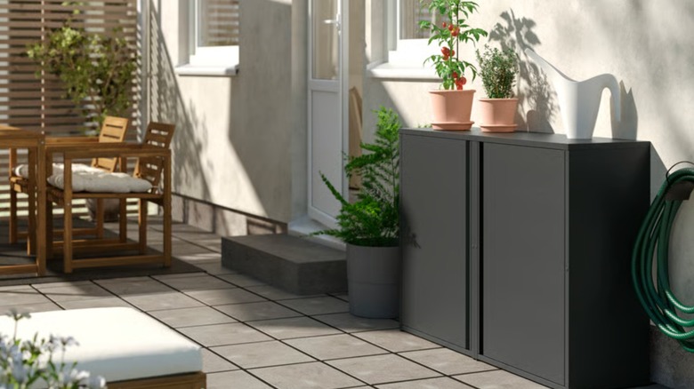 Outdoor patio with IKEA cabinet against a wall with potted plants on top