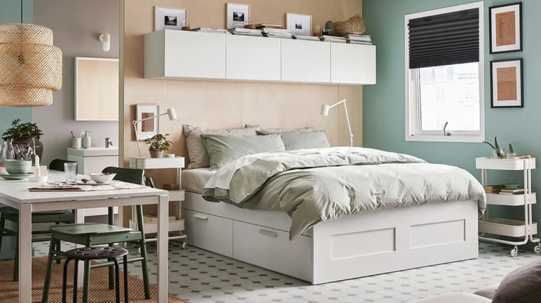 A white bed frame with storage in a studio apartment