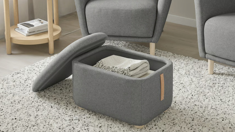 A gray ottoman holding folded blankets