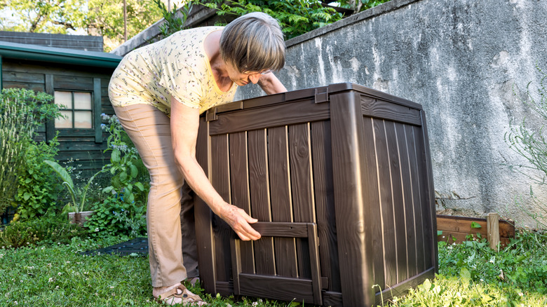 older woman moving a large outdoor storage bin