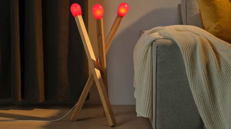 The matchstick lamp from IKEA on the floor next to a couch.