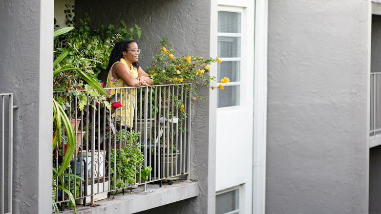 Person enjoying a balcony with plants in an apartment building