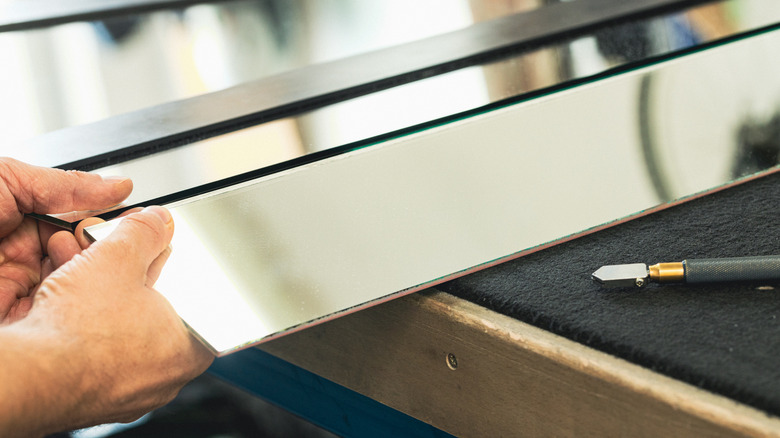 Man cutting mirrors into strips