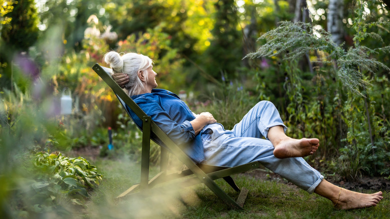 A mature woman relaxes in a garden chair