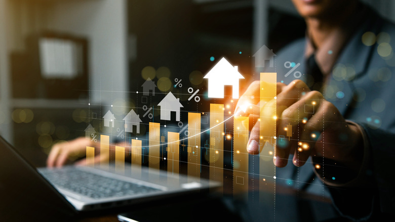 A person sits in front of a computer manipulating a home price bar chart
