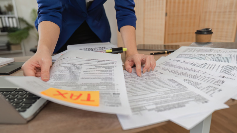 A woman sorts through tax documents on a desk