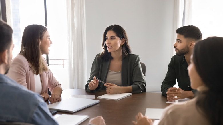 A group of professionals sit at a table having a discussion