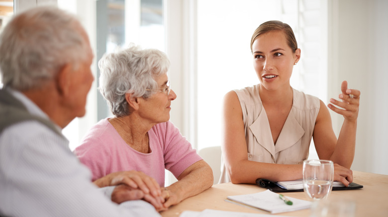 A female professional speaks with an elderly couple