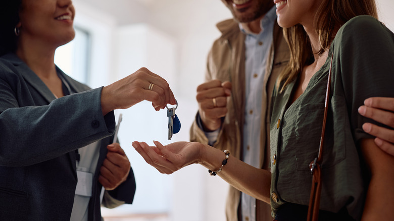 Close up of a couple receiving their keys from a real estate agent