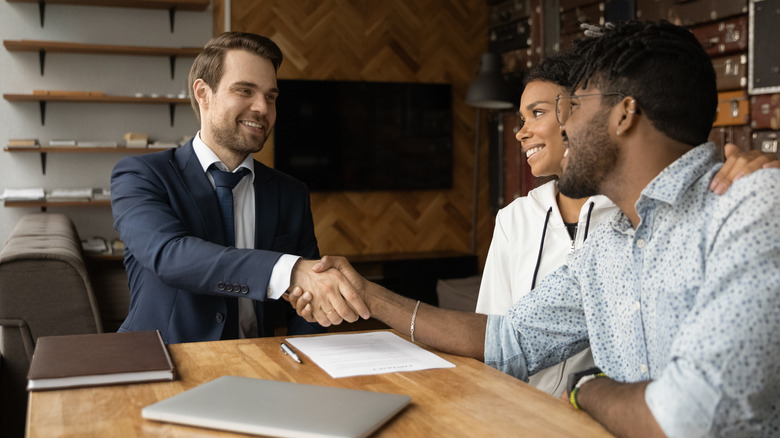 Broker and couple shaking hands