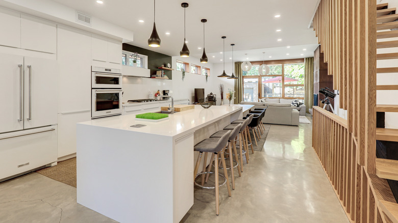 A white island in a kitchen with chairs all around