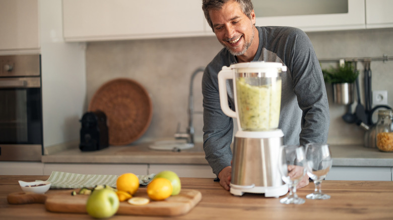 Man running a blender on a wood kitchen island