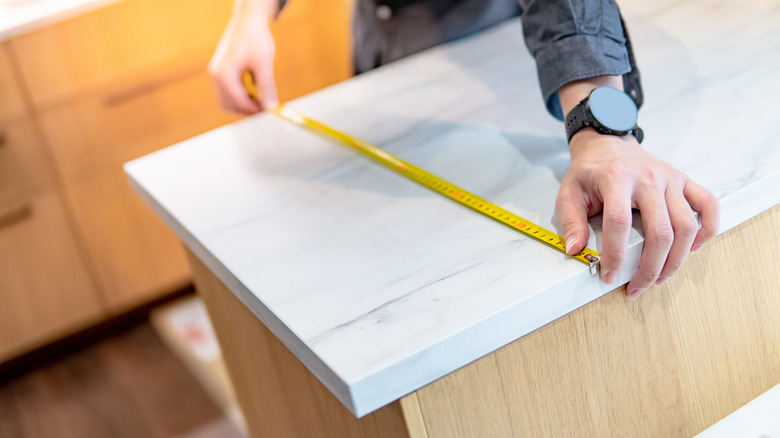 Male hands measuring a kitchen countertop