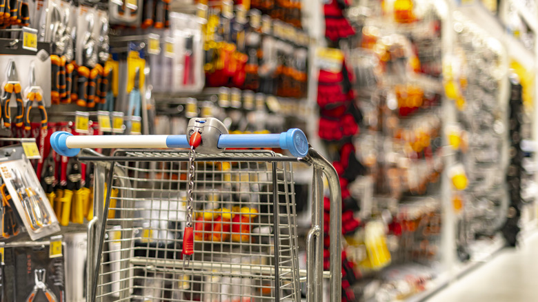 Shopping cart in front of a row of tools in a hardware store