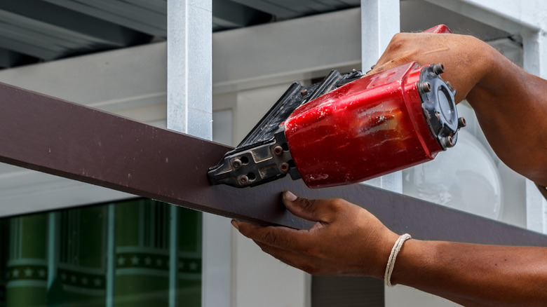 Person shoots nails into a wall with a Milwaukee power tool