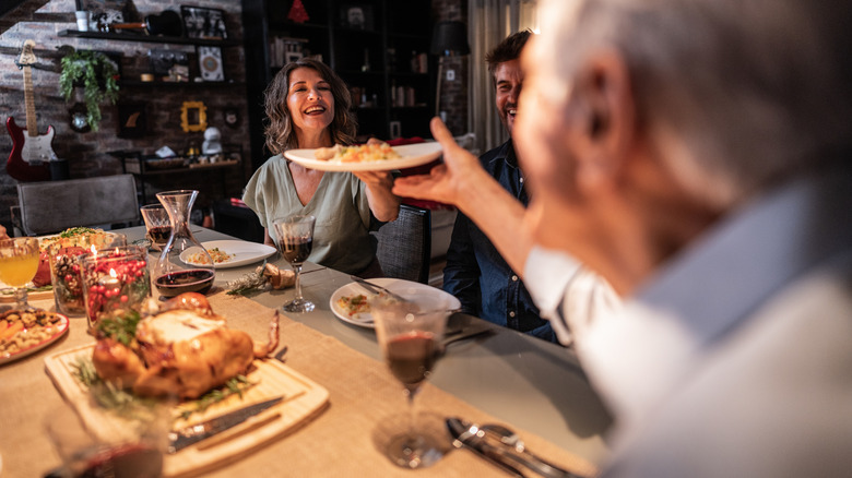 Family members passing a plate over the table at holiday dinner