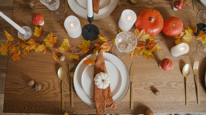A fall tablescape with orange pumpkins and candles.