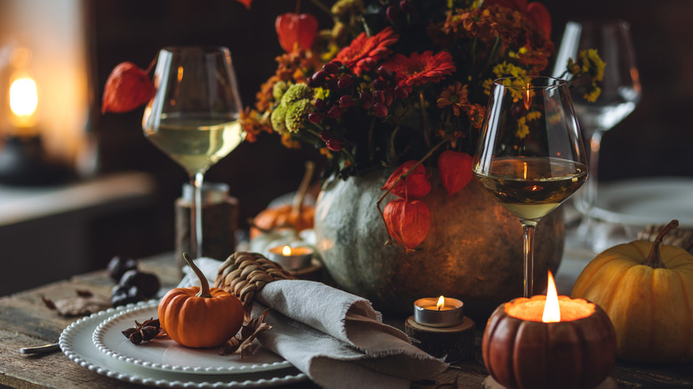 A fall tablescape with orange pumpkins and flowers.