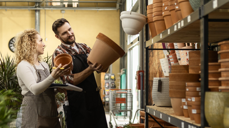 A man and woman look at terracotta pots together in a garden store.