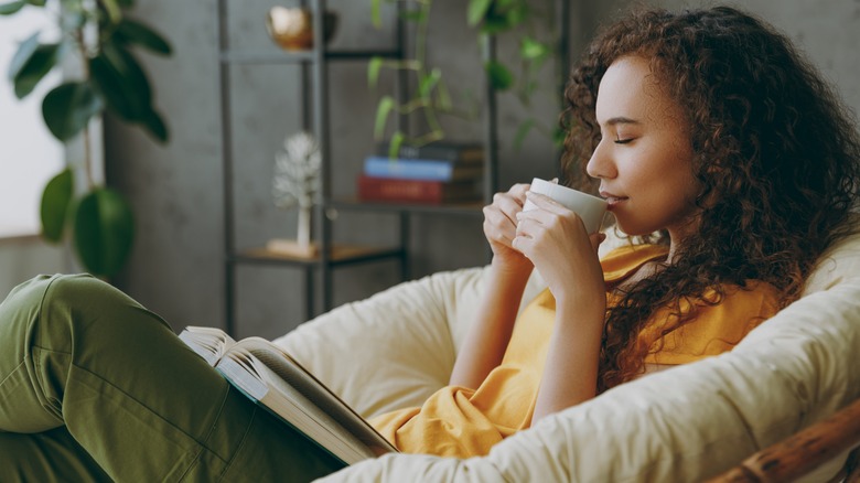 person with book holding mug