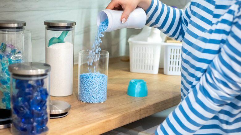a person pours laundry scent beads into a glass jar.